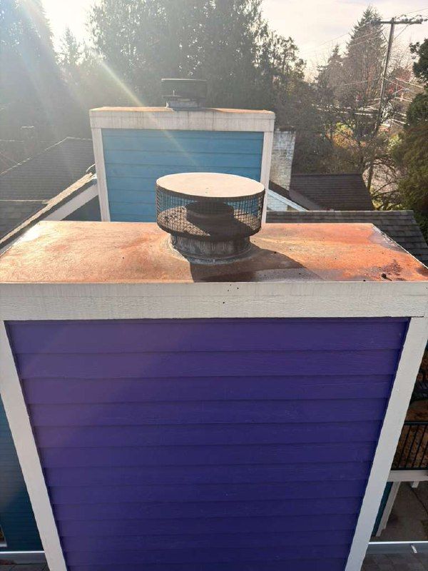 A cracked concrete chimney crown seen from the roof with a flue tile through its center