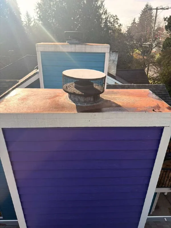 A stained chimney crown under a corroded cap, before the work