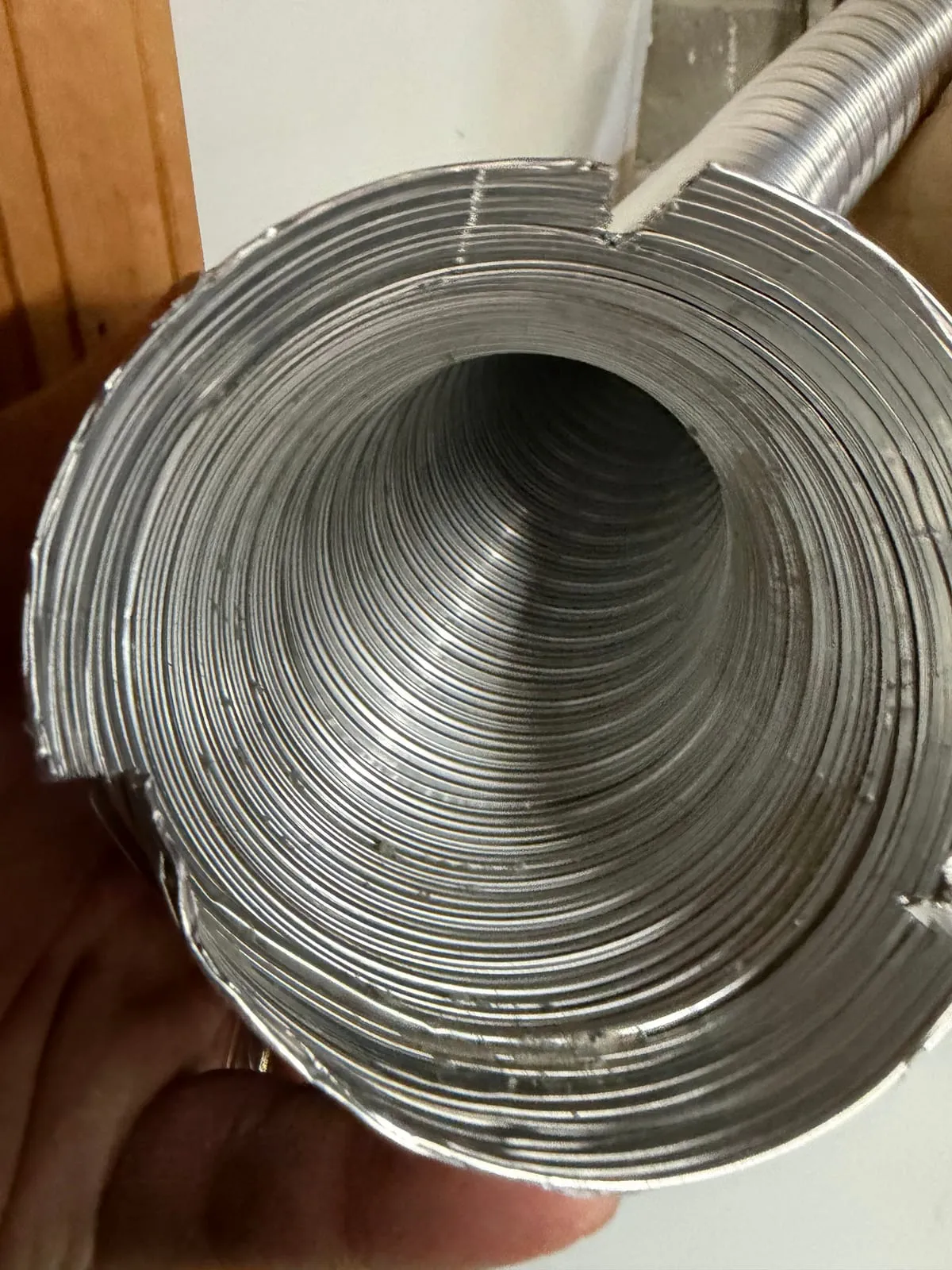 A length of flexible metal ducting held in the hand