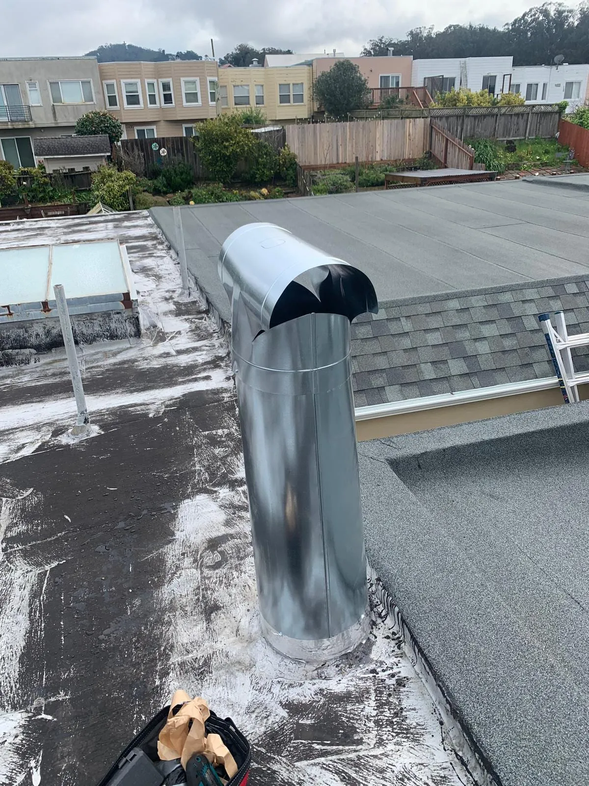A metal flue terminal on an exposed flat roof in urban New Jersey
